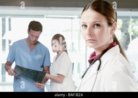 Porträt von einer Ärztin mit ihren Kollegen eine Röntgenaufnahme im Hintergrund prüfen Stockfoto