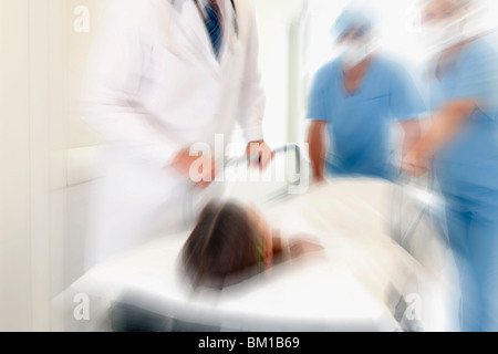 Ärzte schieben ein Patient in einem Krankenhaus Gurney in einem Krankenhausflur Stockfoto