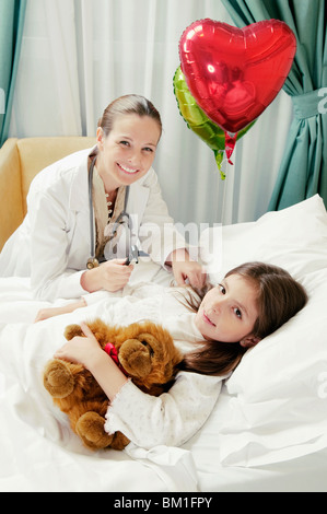 Mädchen in einem Krankenhausbett von einer Ärztin untersucht Stockfoto