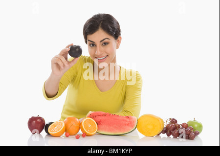 Portrait einer Frau zeigen eine Pflaume und lächelnd Stockfoto