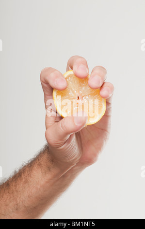 Hand des Mannes drückte eine orange Hälfte Stockfoto