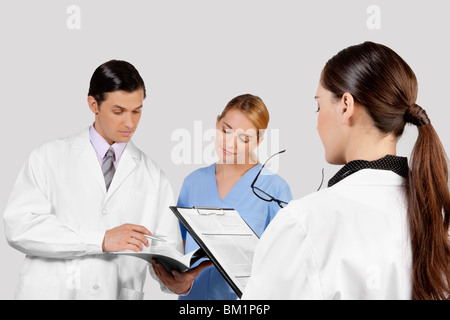 Ärzte und Krankenschwester diskutieren über Krankenakte Stockfoto