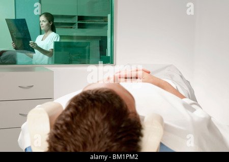 Patienten gehen durch eine MRT-Untersuchung bei einem Arzt einen Röntgenbild der Bericht im Hintergrund wird analysiert Stockfoto
