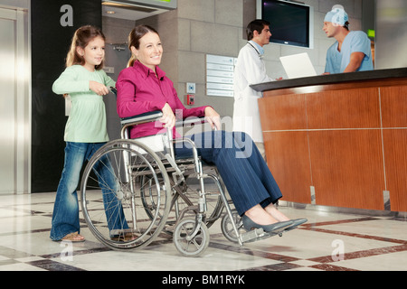 Mädchen, die ihre Mutter im Rollstuhl schieben Stockfoto