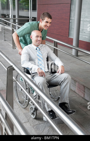 Krankenpfleger, einen Mann im Rollstuhl schieben Stockfoto