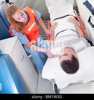 Führen eines Patienten auf einer Bahre in einen Krankenwagen Sanitäter Stockfoto