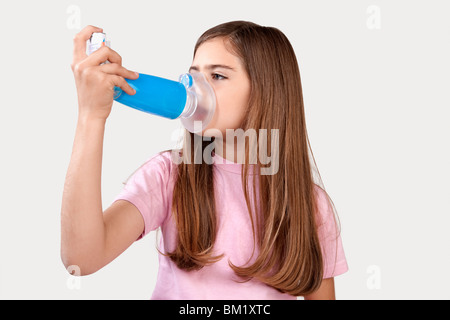 Mädchen mit einem Asthma-Inhalator mit Abstandshalter befestigt Stockfoto