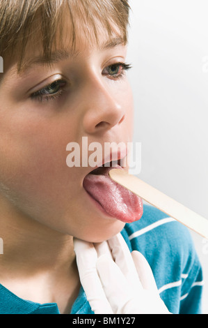 Arzt untersucht einen jungen Mund mit einer Zunge depressor Stockfoto