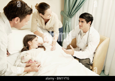 Mädchen auf einem Krankenhausbett und ihre Eltern mit einem Arzt besprechen Stockfoto