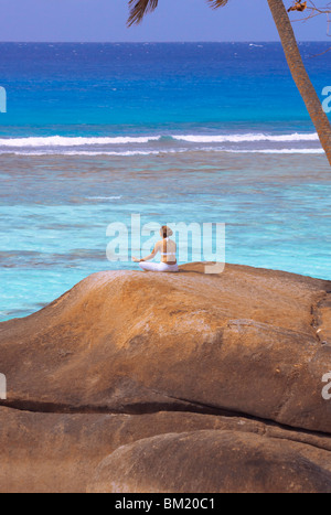 Junge Frau, meditieren auf Felsen, Seychellen, Indischer Ozean, Afrika Stockfoto