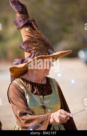 Gainesville, FL - Jan 2009 - Senior Woman in zeitgenössischer Kleidung gekleidet wie eine Hexe Kinder mit Seifenblasen unterhält Stockfoto