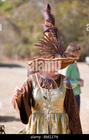 Gainesville, FL - Jan 2009 - Senior Woman in zeitgenössischer Kleidung gekleidet wie eine Hexe Kinder mit Seifenblasen unterhält Stockfoto