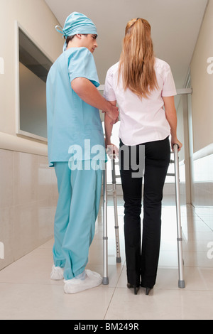 Arzt, die Unterstützung eines Patienten in einem Krankenhausflur gehen Stockfoto