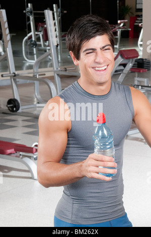Mann hält eine Flasche Wasser und lächelnd in ein Fitness-Studio Stockfoto