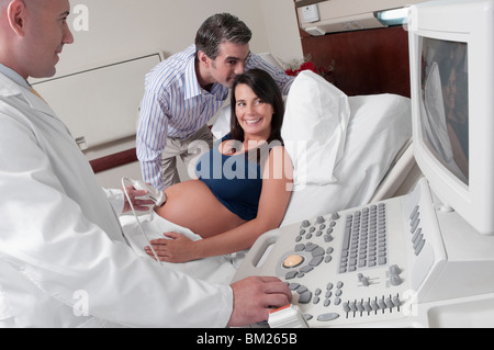 Schwangere Frau geht durch eine Ultraschalluntersuchung mit ihrem Mann neben ihr Stockfoto