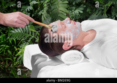 Kosmetikerin auftragen Gesichtsmaske auf das Gesicht des Mannes Stockfoto