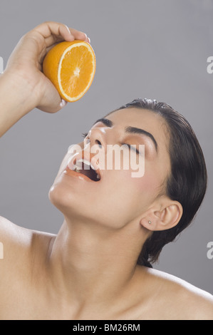 Nahaufnahme einer Frau drückte Saft von einer halben Orange in den Mund Stockfoto