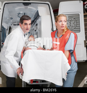 Führen eines Patienten auf eine Bahre von einem Krankenwagen Sanitäter Stockfoto