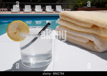 Glas Limonade mit Handtüchern am Pool Stockfoto