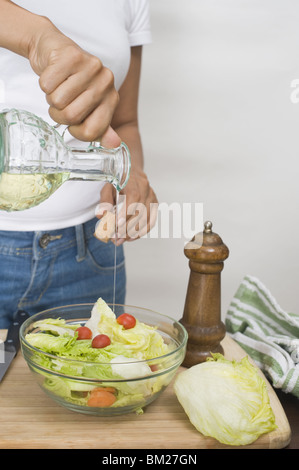 Mitte Schnittansicht einer Frau in Gießen Öl in eine Schüssel geben Stockfoto