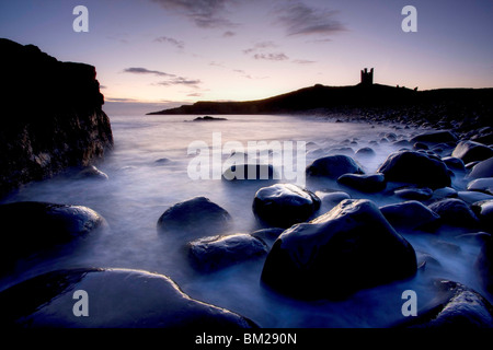 Blick über den Rumble Churn im Morgengrauen zu den Ruinen der Dunstanburgh Castle, Embleton Bay, Northumberland, UK Stockfoto