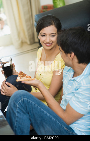 Mann einer Frau ein Stück Pizza anzubieten Stockfoto