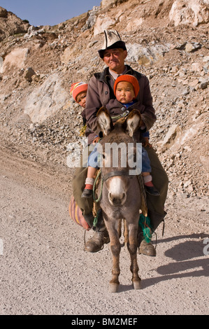 Mann mit Zwillingen auf Esel in den Bergen in der Nähe von Sary Tash, Kirgisistan Stockfoto