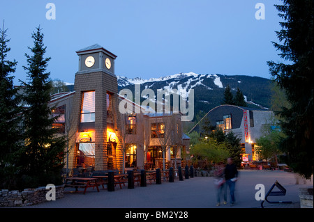 Whistler Village in der Dämmerung mit dem Brew Pub Restaurant und Uhrturm mit Blackcomb Mountain im Hintergrund Stockfoto