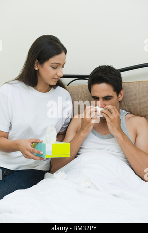 Frau mit Tissue-Papiere mit einem Mann zum Ausblasen der Nase Stockfoto