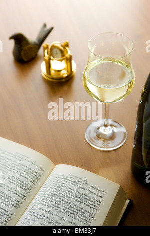 Weißwein, Buch, Uhr und Bird Figurine auf einem Schreibtisch Stockfoto