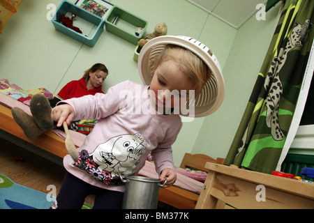 VERRÜCKTES SÜSSES KLEINKIND-MÄDCHEN, DAS SO SPIELT: Kleinkinder Mädchen Baby spielt Tragen trägt ein Sieb, als ein Hutmodell veröffentlicht wird Stockfoto