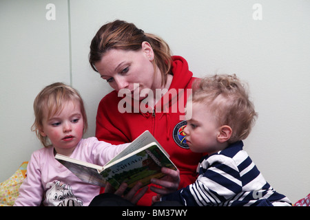MAMA LIEST BUCH FÜR ZWEI KLEINKINDER: Mama Mutter liest vor ihren Kindern Kleinkinder Junge Mädchen Baby Babys Model veröffentlicht Stockfoto