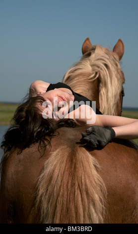 Reiterin auf einem braunen Pferd laufen auf einer wilden Wiese Stockfoto