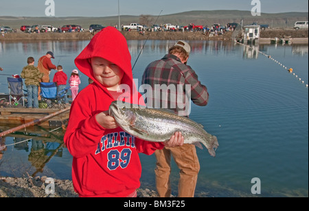 Diese kleinen kaukasischen jungen hält stolz seinen Preis Forelle Fisch, die er beim Angeln-Derby am 16. April 2010 gefangen. Stockfoto