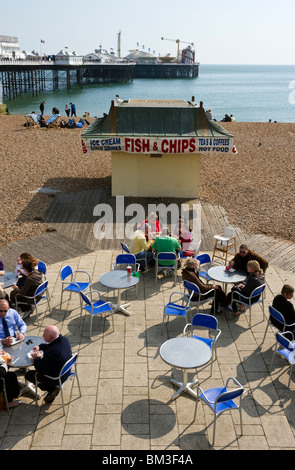Menschen, Touristen, Ausflügler sitzen an Tischen und Stühlen in einem Straßencafé auf Brighton vorne Sussex UK Stockfoto