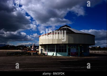 Jolly Roger Restaurant, ein rundes Gebäude gegen einen dramatischen Himmel auf Clacton Pier Essex UK Stockfoto