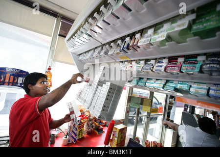 Ein Convenience-Store Clerk bei einer Tankstelle füllt Zigarette Inhaber hinter der Theke. Preise sind aufgrund von Steuern wieder gestiegen. Stockfoto