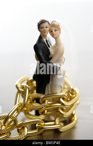 Metapher der Ehe als ein Verlust an Freiheit. Hochzeit-Figuren und goldene Kette Stockfoto