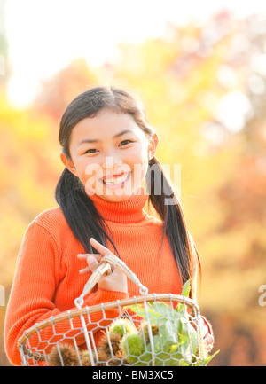 Portrait von Mädchen, dass Kastanien Korb, Herbst Farbe Bäume im Hintergrund Stockfoto