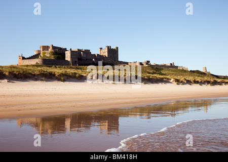 Bamburgh Castle spiegelt sich in nassem Sand am ruhigen, leeren Strand an der Küste Northumbrias wider. Bamburgh Northumberland England, Großbritannien. Stockfoto