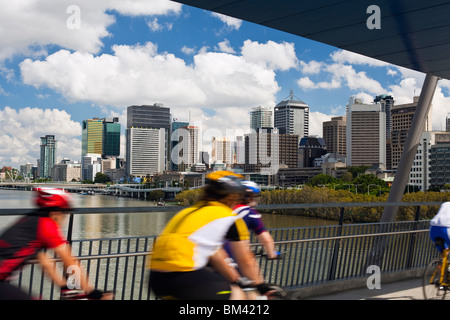 Radfahrer auf der Geschäfts-oder Firmenwert-Brücke mit der Stadt Skyline im Hintergrund. South Bank, Brisbane, Queensland, Australien Stockfoto