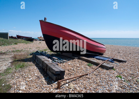 Eine rote und schwarze Ruderboot festgemacht an einem Strand gespeicherten Stockfoto