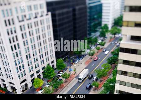 K Street Downtown Tilt-Shift Washington DC | WASHINGTON D.C., Vereinigte Staaten – Ein Foto mit Neigeverschiebung verwandelt den Verkehr in der K Street und der 19th Street in eine spielzeugähnliche Miniaturszene. Die Technik verwendet ein schmales Band mit scharfem Fokus, um die geringe Tiefe des Feldes der Makrofotografie nachzuahmen, wodurch das Auge dazu verleitet wird, große Gebäude und Fahrzeuge als maßstabsgetreue Modelle zu lesen. Die K Street ist ein wichtiger Geschäftskorridor, der lange mit Washingtons Lobbyarbeit und Anwaltskanzleien verbunden ist. Stockfoto