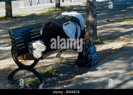 Obdachloser schlafen auf einer Bank Stockfoto