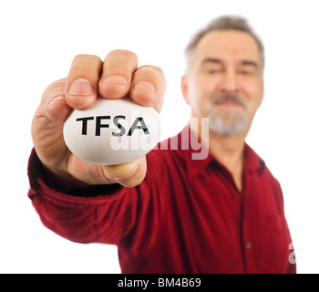 Reifer Mann hält ein Ei mit TFSA drauf. TFSA ist ein Tax-free-Sparkonto, eine beliebte Investition Werkzeug in Kanada. Stockfoto
