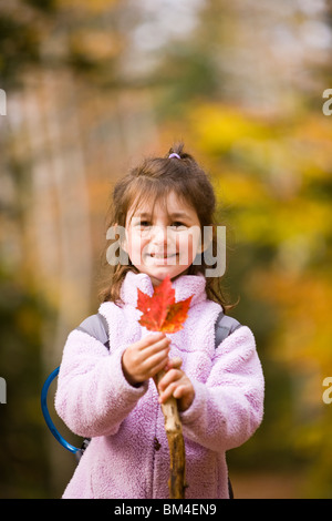 Ein junges Mädchen (6 Jahre) spielt mit abgefallenen Blättern auf dem Lincoln Woods Trail in New Hampshire White Mountain National Forest. Stockfoto