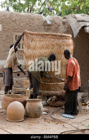 Eine Gruppe Männer bauen ein Grainery aus geflochtenen Matten aus Stroh in Kalabougou, Mali. Stockfoto