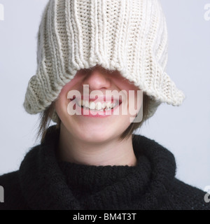 Lächelnde Mädchen Abdeckung Augen mit einer Wollmütze. Stockfoto