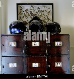 Drei Motorradhelme auf einen alten Holzschrank Stockfoto