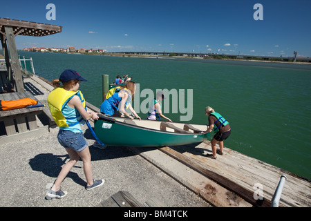 Mittelschule Mädchen das Tragen von Schwimmwesten ziehen Sie eine grüne Kanu auf das Wasser des Corpus Christi Bay in der Nähe von Corpus Christi, Texas während Schulausflug. Stockfoto